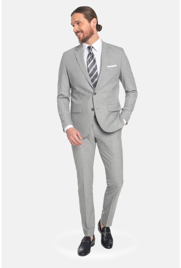 Mężczyzna ubrany w szary garnitur, białą koszulę i szaro-biały krawat oraz czarne buty