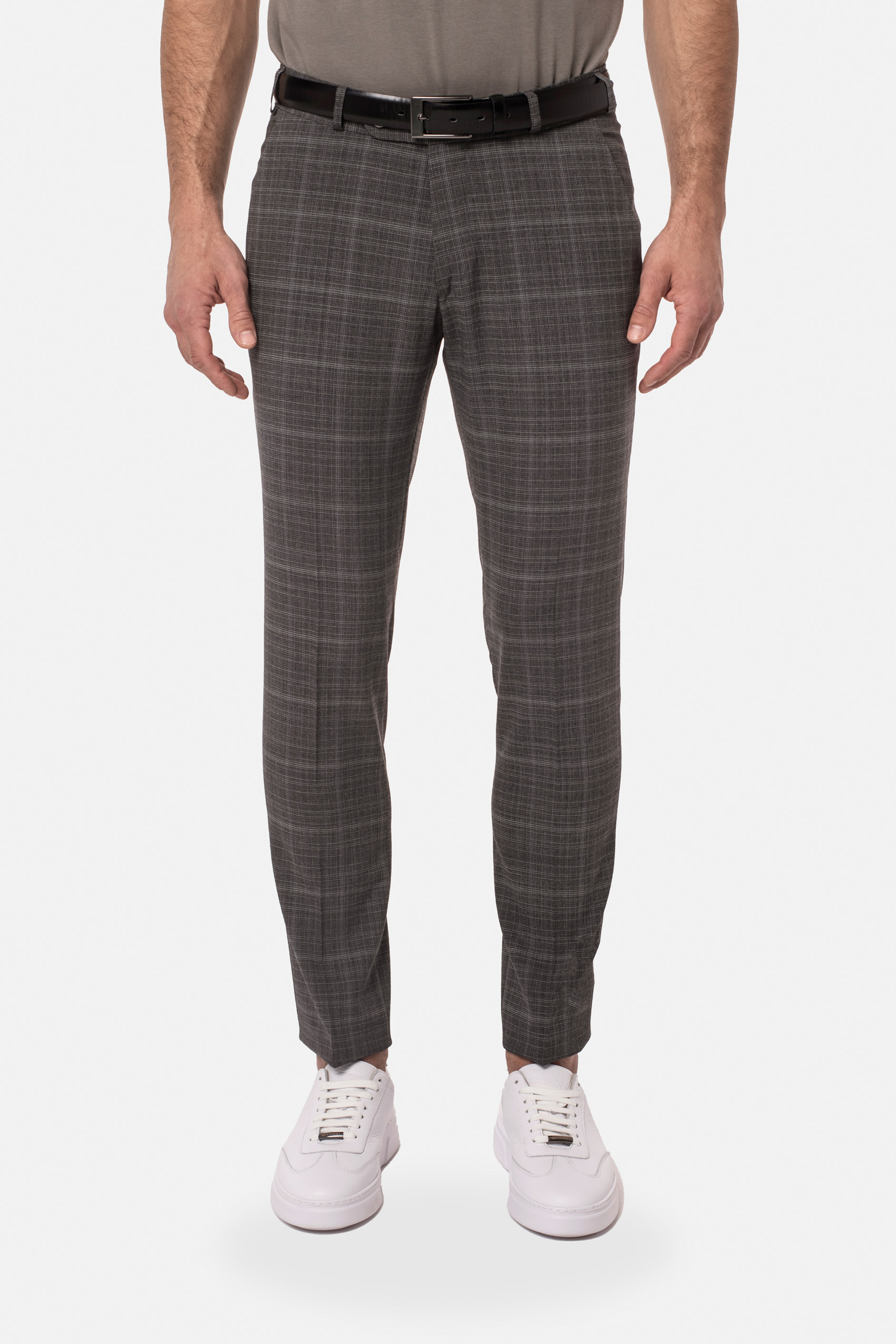Mężczyzna ubrany w spodnie w kratę w kolorze ciemnego beżu z czarnym paskiem i białymi butami