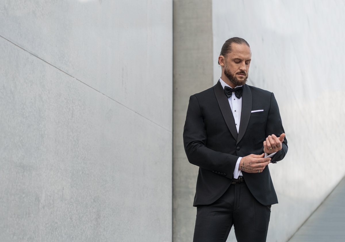 Mężczyzna ubrany w czarny smoking, białą koszulę i czarną muchę