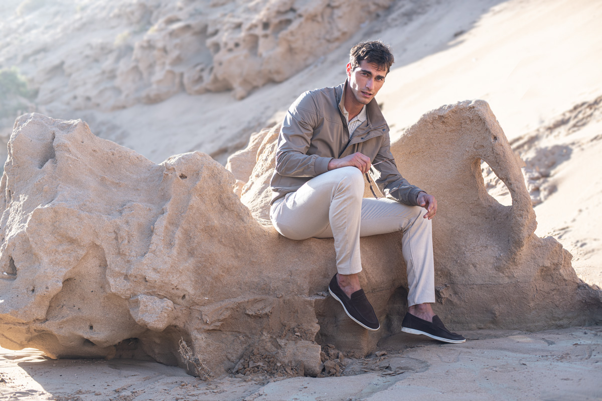 Mężczyzna ubrany w beżową kurtkę, jasne spodnie i monki