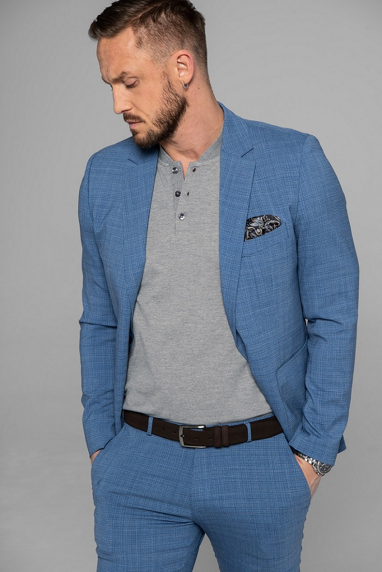 Model ubrany w jasnoniebieską marynarkę i spodnie w kratę, szarą koszulkę polo z poszetką i czarnym paskiem
