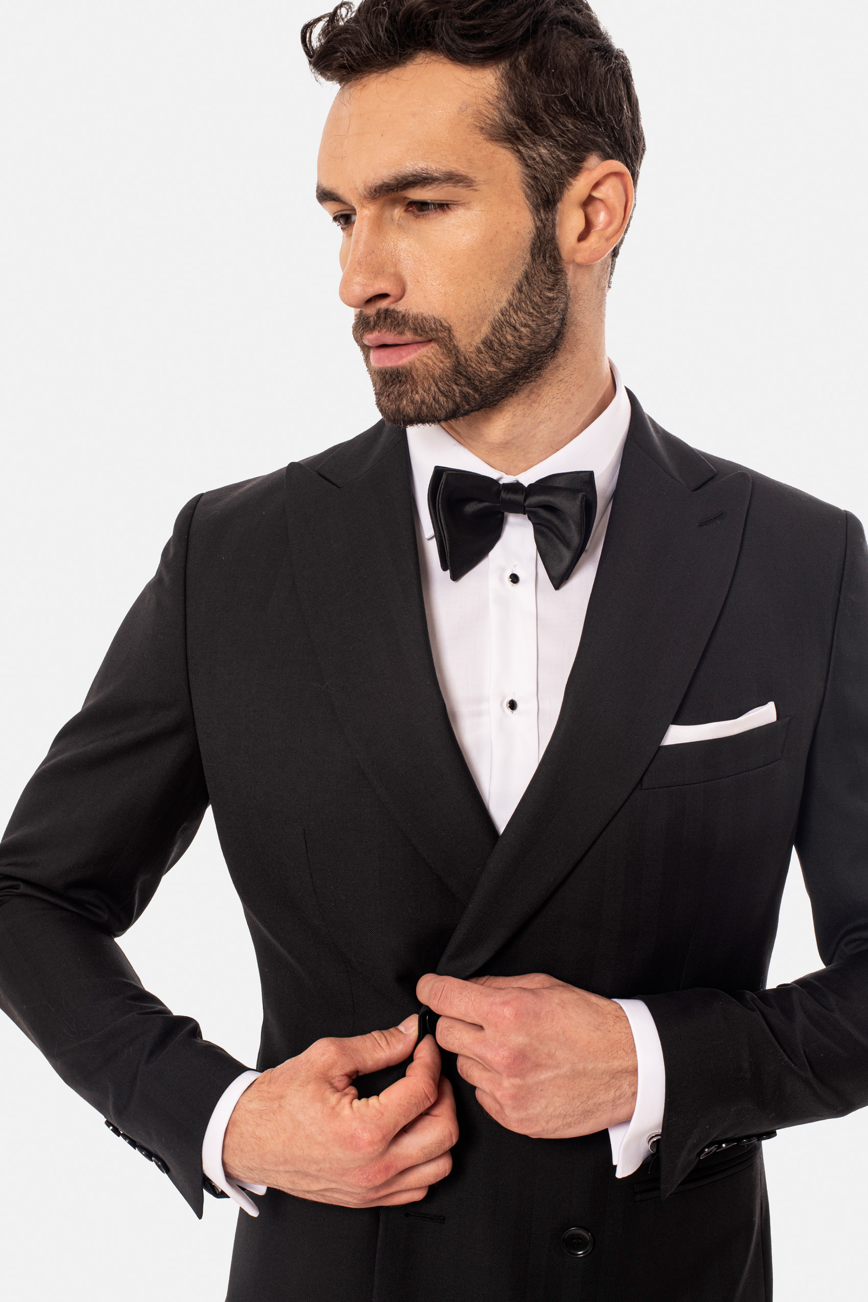 Mężczyzna ubrany w czarny garnitur, białą koszulę i czarną muszkę