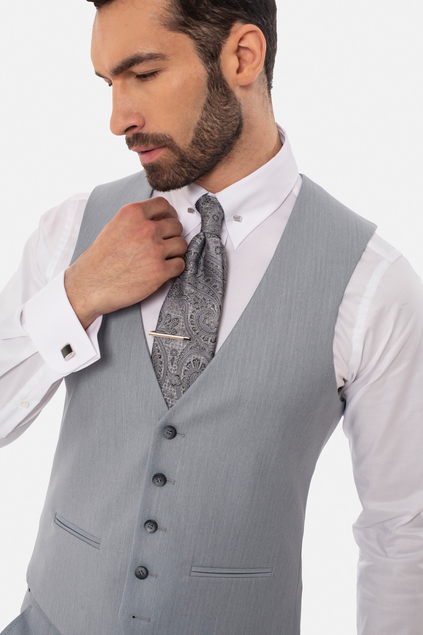 Mężczyzna ubrany w białą koszule, szarą kamizelkę i szary krawat ze spinką